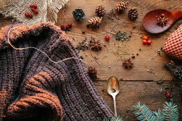 Details of still life in the living room home interior. Beautiful cup of tea with spices and sweaters on a wooden background. Cozy autumn-winter concept.