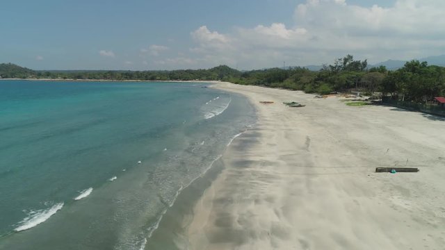 Beautiful tropical beach Cabugao with white sand and palm trees in the Philippines, Luzon. Aerial view of coast with beach and turquoise water.