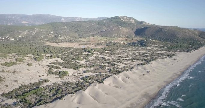 Medium altitude forward aerial drone video descending towards angled long empty Patara beach and large sand dune landscape in Turkey. 4k at 23.97fps