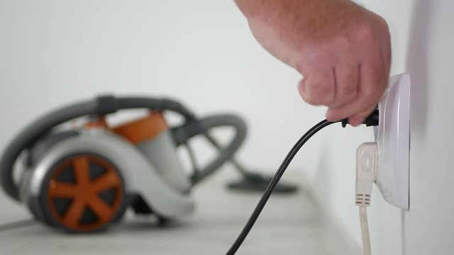 Man Plug-In Vacuum Cleaner in Electric Socket and Start Cleaning Office Floor