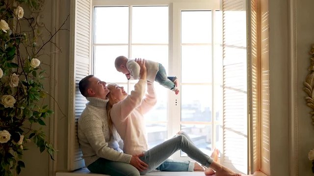 parents and boy child sitting on the window in sweaters