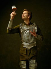 Medieval knight with beer on dark studio background. Portrait in low key of brutal man in...