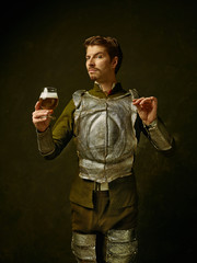 Medieval knight with beer on dark studio background. Portrait in low key of brutal man in...