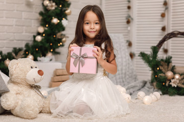 Pretty smiling girl holding Christmas gift in hand