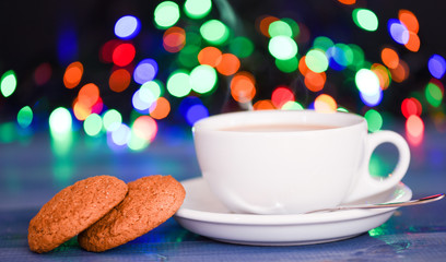 Fresh brewed coffee in white cup or mug on defocused garland lights background. Coffee drink winter holiday new year. Enjoying coffee on christmas morning. Coffee time christmas eve