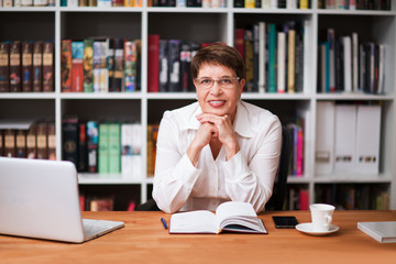 Portrait of  senior businesswoman wearing glasses head shot in a white shirt, looking at the camera...