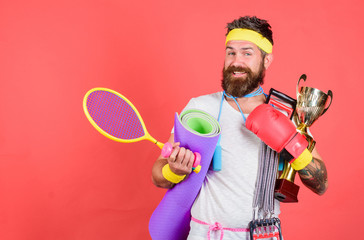 Man bearded athlete hold sport equipment jump rope fitness mat boxing glove expander racket and...