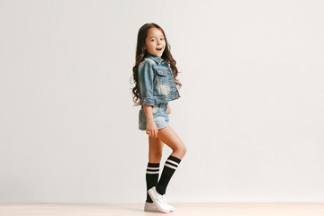 Full length portrait of cute little kid girl in stylish jeans clothes looking at camera and...