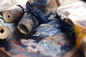 used tubes of paint, illuminated by the sun, lie on the palette