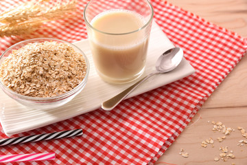 Oat drink in glass and cereal flakes in bowls elevated