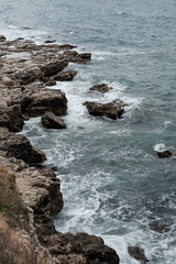 Steep rocky shore and blue sea waves