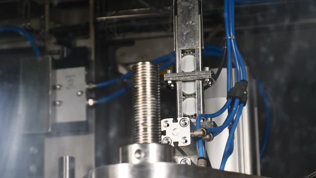 Robotic Touch. Closeup Shot of a Production Machine. Bottle Caps moving to be placesd on beer Bottles on the Conveyor. Technological line. Beer production. Brewery concept. 4k