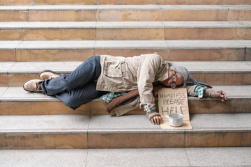 Old man homeless sleeping on stairs in urban