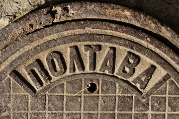 Vintage cast-iron sewer manhole USSR made with the inscription POLTAVA in the city of Dnipro, Ukraine, November 2018 (fragment). Theft of manhole covers has become a frequent occurrence since 2014.