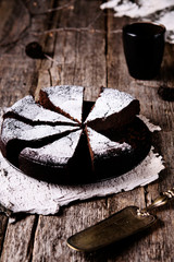 Kladdkaka. Traditional Swedish moist chocolate cake on old rustic wooden table decorated dry twigs, pine cones and birch bark. Fika. Hygge