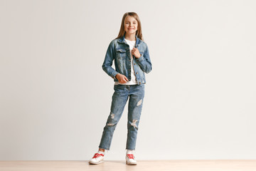 Full length portrait of cute little teen girl in stylish jeans clothes looking at camera and...