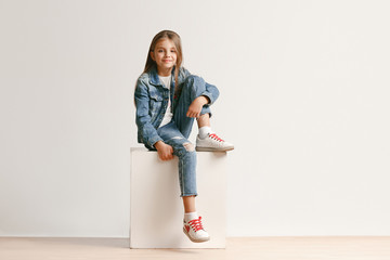 Full length portrait of cute little teen girl in stylish jeans clothes looking at camera and...