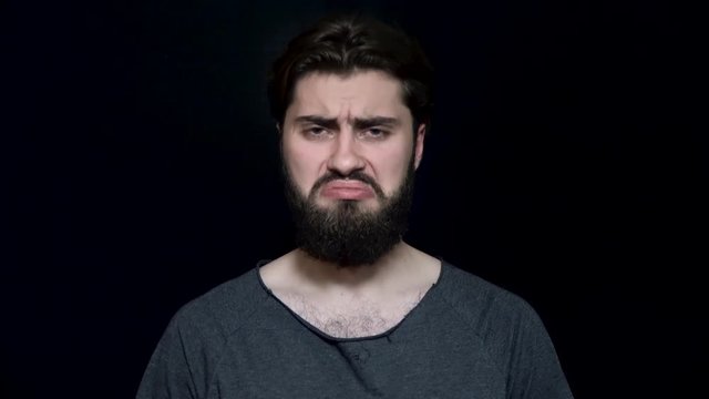 Man with beard frowned sadly and upset. Young man with beard looks sad and offended with frowning face. Human facial expressions and emotions