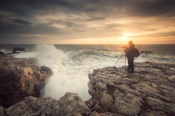 Sunrise on a rocky beach / Silhouette of a photographer taking photos of the sunrise