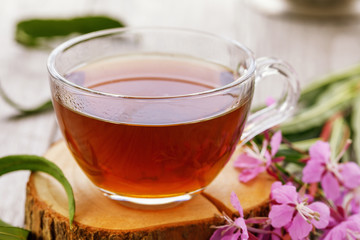 Traditional Russian herbal drink Ivan-tea in transparent cup close-up on wooden table