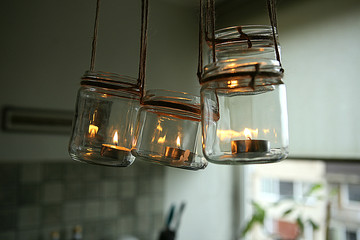 Aromatic candles in glass jars hanging in kitchen. DIY candles in glass jars hanging on linen jute. 