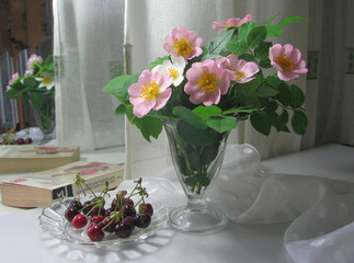 Obraz na płótnie Canvas Still life. A bouquet of a pink jasmine in a glass vase. Plate of cherry, sweet cherry. Spring.