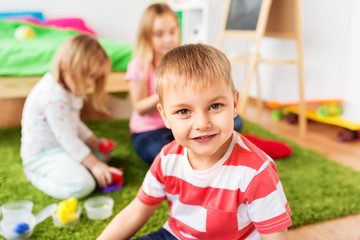 Obraz premium childhood, leisure and people concept - cute little boy over children playing with modelling clay or slimes at home