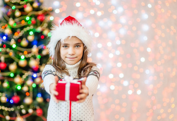 Happy little girl holding christmas present box for you