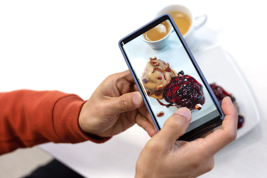 close up of young man using smart phone taking photo which take a picture food or bakery before eating, photography on white background
