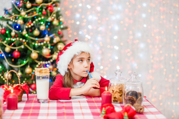 the girl thinks what to write in a letter to Santa Claus and looks away. Empty space for text