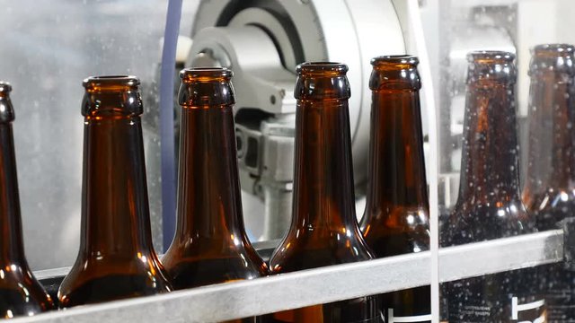 Robotic Touch. Closeup Shot of a Production Machine in brewery. Empty beer Bottles on the Conveyor. Technological line. Beer production. Brewery concept. 4k
