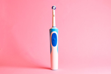Modern electric toothbrush and spare heads on pink background