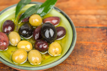 Olives in oil on wooden table.