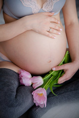 Fototapeta na wymiar pregnant woman in lingerie is holding a tulips