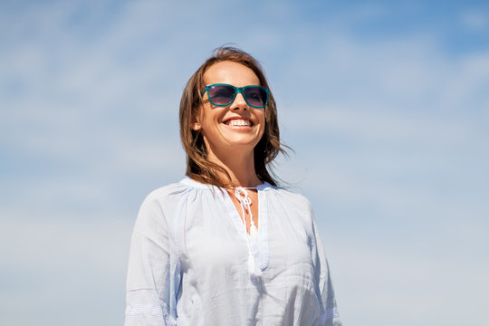people and leisure concept - happy smiling woman in sunglasses over sky