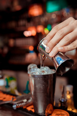 Barman pouring a cocktail into a glass