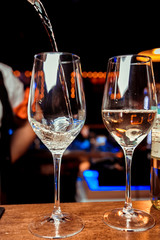 Pouring white wine into glasses in the vineyard, toned