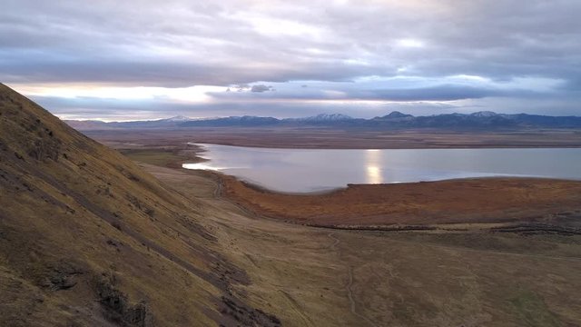 View of lake and mountains in aerial view with cloudy sky at dusk.