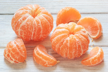 Tangerine mandarines peeled on white wooden table background