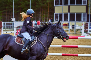 Young woman jockey in white black dress and black boots, takes part in equestrian competitions. Close-up.
