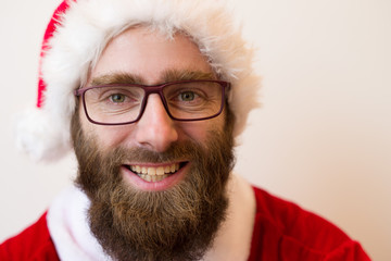 Smiling bearded man wearing Santa Claus costume and glasses. Handsome guy looking at camera. Christmas concept. Isolated front view on white background.