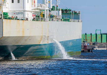 Tanker discharging ballast into the harbor. Water flows from the side. Ship not identifiable. Only...