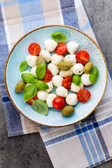Delicious caprese salad with ripe cherry tomatoes and mini mozzarella cheese balls with fresh basil leaves.