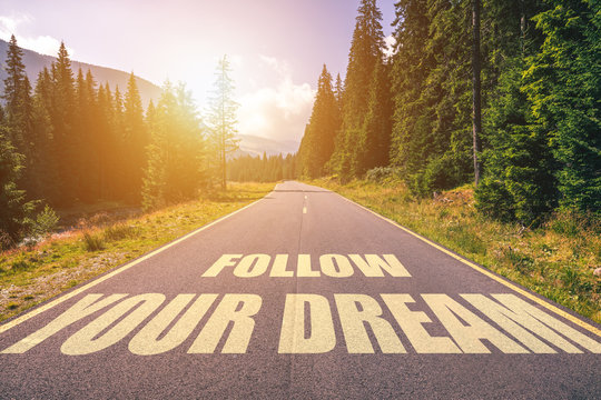 Follow your dream text written on road in the mountains