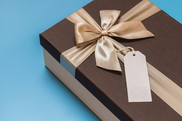 Close up on a gift box with a blank label attached on a blue background.