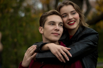 girl hugs a guy and smiles, autumn. hug from behind. portrait