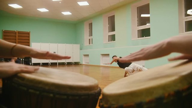 Fighter performs martial tricks on background playing a two musical instruments atabaque