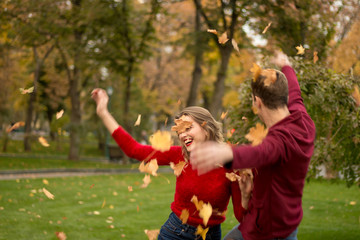 Fototapeta premium a couple throws up yellow leaves, maple, up, fooling around, autumn. date