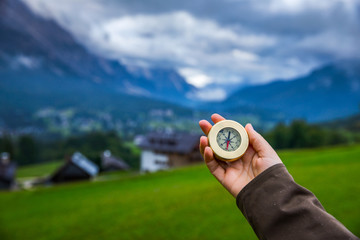 Explorer searching direction with compass in summer mountains, point of view.