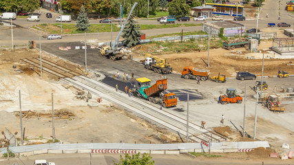 Asphalt paver, roller and truck on the road repair site during asphalting timelapse. Road construction equipment.